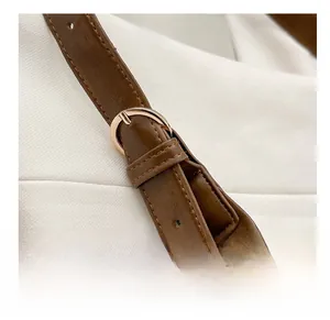 Close-up of brown leather shoulder strap with a gold adjustable metal buckle and stitching