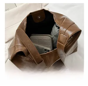 Macro view of brown PU leather tote bag showing large interior space with wallet and umbrella