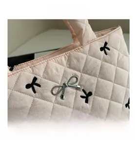 Detail of pink quilted tote bag with black bow embroidery and silver metal bow charm