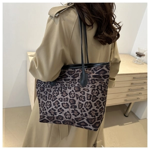 Detailed side view of large leopard print tote bag with black leather shoulder straps