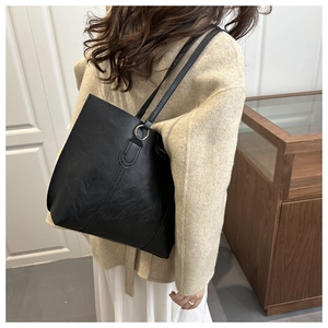Detail view of black textured leather tote bag with vertical stitching and metal ring hardware