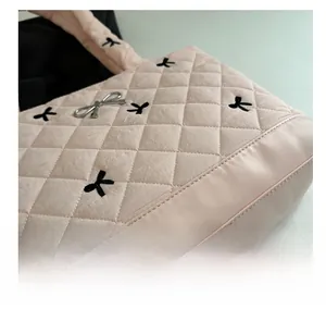 Close-up of pink quilted tote bag with black ribbons and silver butterfly charm