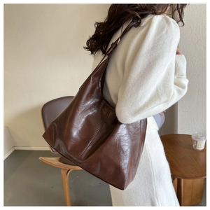 Side view of dark brown faux leather tote bag showing spacious design and strap detail