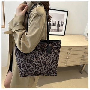 Detailed shot of leopard print tote bag with black leather handle on khaki trench coat