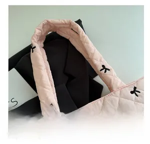 Close-up of pink quilted tote bag with black bow embroidery and silver metal charm