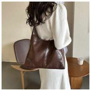 Detail view of smooth dark brown patent leather tote bag on shoulder for daily commute