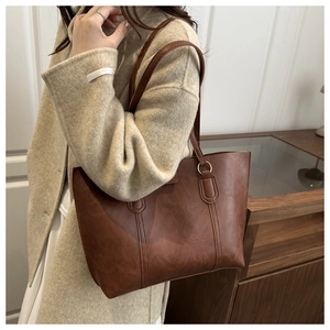 Detail shot of the brown PU leather tote bag texture and metal strap buckle