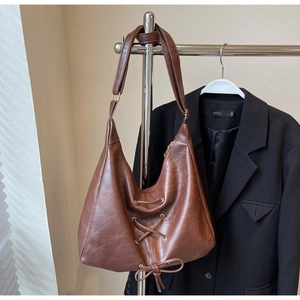 Dettaglio della borsa tote vintage marrone scuro con lacci incrociati e fiocco decorativo