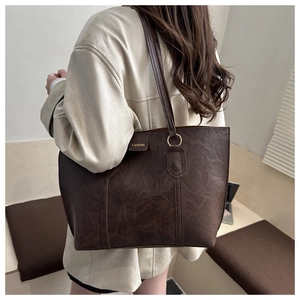 Detail view of large dark brown tote bag with retro leather texture and golden metal rings