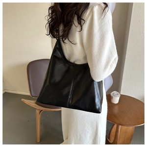 Detail view of the large black minimalist tote bag showing soft leather texture and stitch