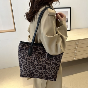 Chic leopard print tote bag with black leather straps shown on model for daily commute