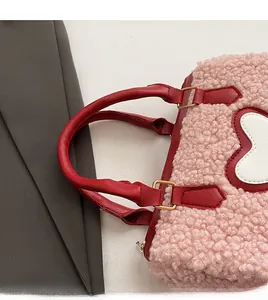 Detailansicht der rosa Sherpa-Tasche mit weißem Herz-Patch und rotem Ledergriff