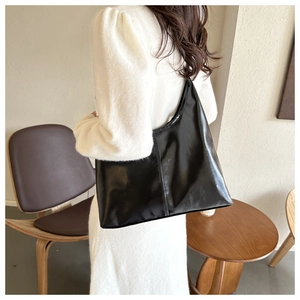 Detail of glossy black faux leather tote bag showing smooth texture and large capacity
