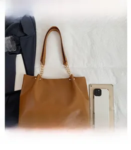 Comparaison de taille du sac fourre-tout en cuir marron avec tablette et téléphone