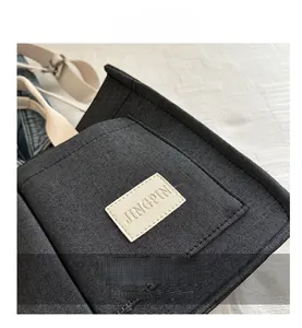 Gros plan détaillé du cabas en toile noire avec texture sergé et écusson logo en cuir
