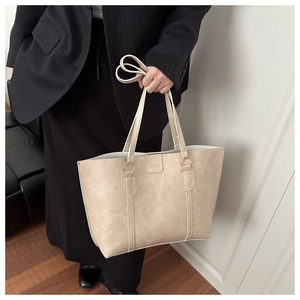 Detail of beige tote bag with gold metal rings and a Fashion leather patch decoration