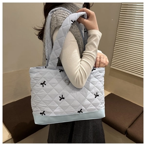 Quilted light blue tote bag with black bow embroidery and metallic bow charm detail