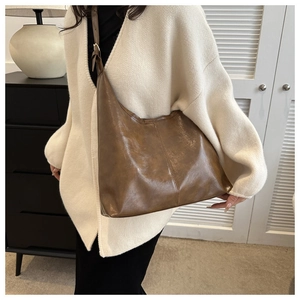 Brown faux leather hobo bag worn by model in a minimalist indoor home setting