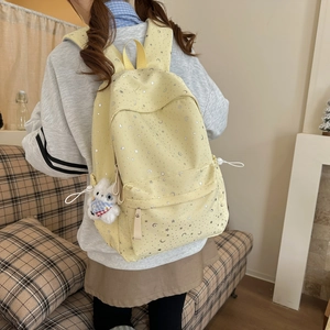 Star and moon pattern yellow backpack with plush bear charm worn by a girl