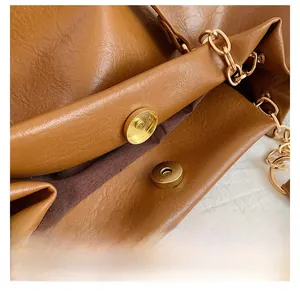 Détail de la boucle magnétique dorée et cuir grainé de la grande besace marron à chaîne