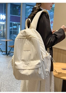 Detail view of white minimalist backpack with unique crinkled fabric texture in cafe setting