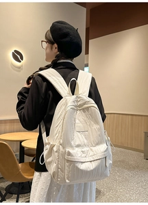 Detail view of cream white nylon backpack with textured fabric and front pocket