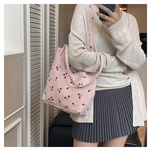Dettaglio ravvicinato della borsa tote in velluto rosa con ricami a forma di ciliegia