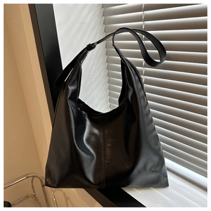 Detail view of large black PU leather tote bag featuring adjustable strap and vertical stitching