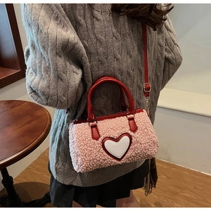 Detail der rosa Plüsch-Umhängetasche mit weißem Herz-Patch und rotem Lederriemen