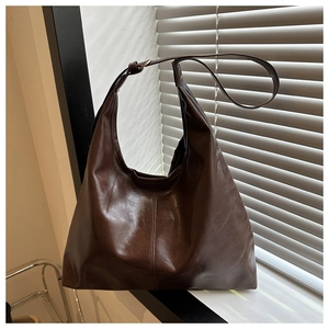 Detail of a dark brown large Hobo shoulder bag with glossy leather and vertical stitching