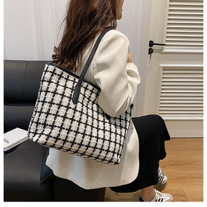 Dettaglio della grande borsa tote in tweed a quadri con manici neri su una modella