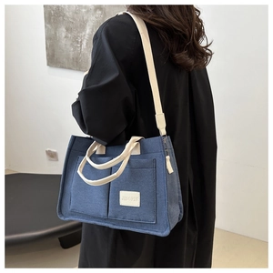 Détail du sac cabas bleu en toile avec bandoulières et poches avant avec étiquette JINGPIN