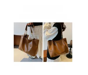 Détail d'un sac cabas marron en cuir avec bandoulière chaîne et texture grainée