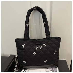 Detail of black quilted tote bag with silver bow embroidery and leather base panels