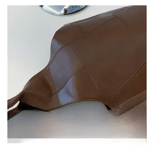 Close-up of brown leather texture and grid stitching on a large vintage tote bag