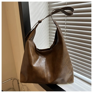 Detailed view of deep brown faux leather shoulder bag with sleek stitching and wide strap