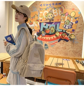 Minimalist beige backpack with corduroy texture and front pocket shown in a lifestyle scene
