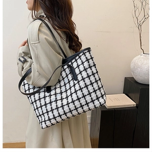 Dettaglio della grande borsa tote a quadri bianca e nera con cinturini in pelle su modella