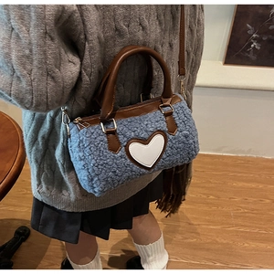Detail der blauen flauschigen Plüschtasche mit braunen Ledergriffen und weißem Herz-Aufnäher