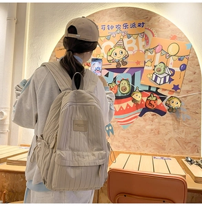 Detail view of the beige nylon backpack showing textured fabric and front zipper pocket