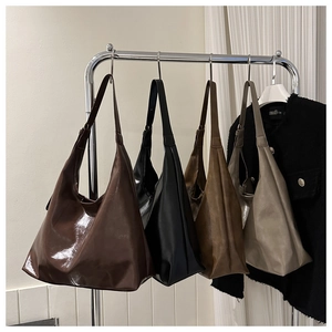 Detail shot of oversized minimalist hobo bags in deep brown, black, tan, and light gray colors
