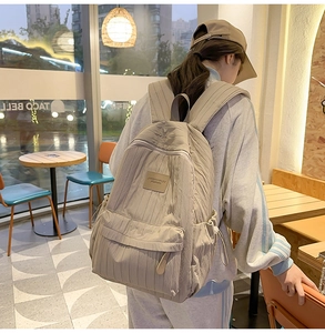 Detail of khaki backpack featuring vertical quilted texture and side drawstring pockets