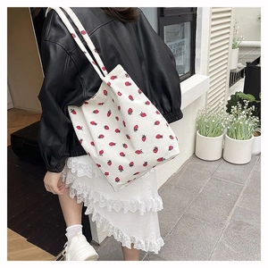 Dettaglio della borsa tote in velluto a coste bianco con stampe di fragole rosse e verdi