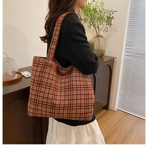 Close-up of a plaid tweed tote bag with a wooden button on a model's shoulder