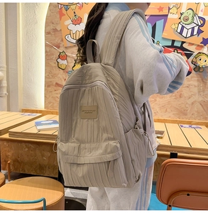 Detail showing the vertical pleated texture and side pocket of the khaki backpack