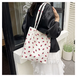 Dettaglio borsa shopper minimalista in velluto a coste crema con stampa fragole a tracolla