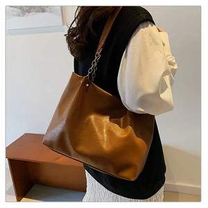 Détail de la texture en cuir marron et bandoulière en chaîne du grand cabas
