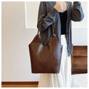 Detail of a large brown tote bag showing the unique geometric patchwork texture design
