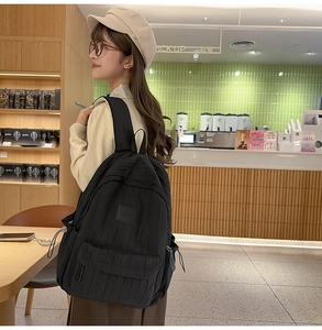 Detail of minimalist black quilted backpack showing vertical texture and side pockets