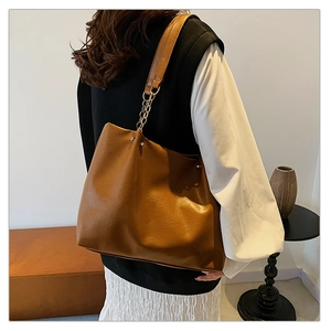 Gros plan sur le sac cabas marron texturé avec bandoulière en chaîne dorée élégante